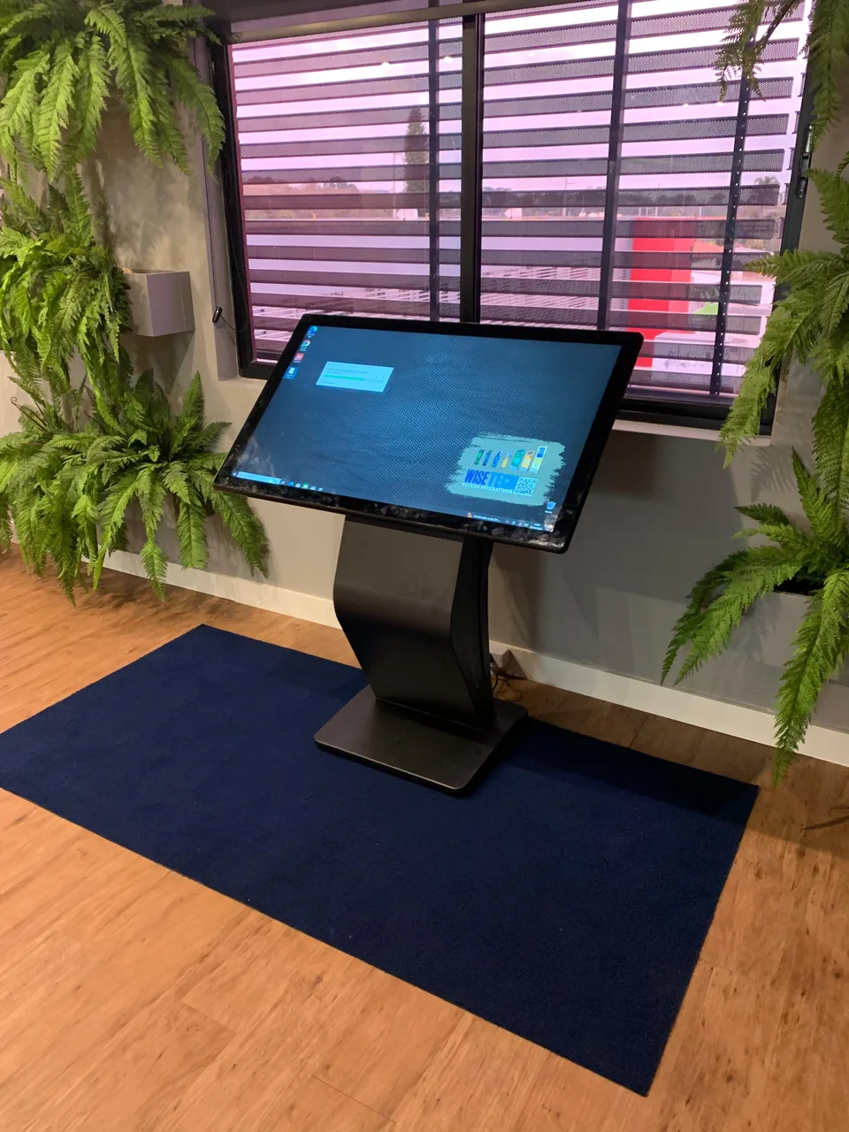 Totem horizontal instalado em espaço com vegetação e painel de madeira