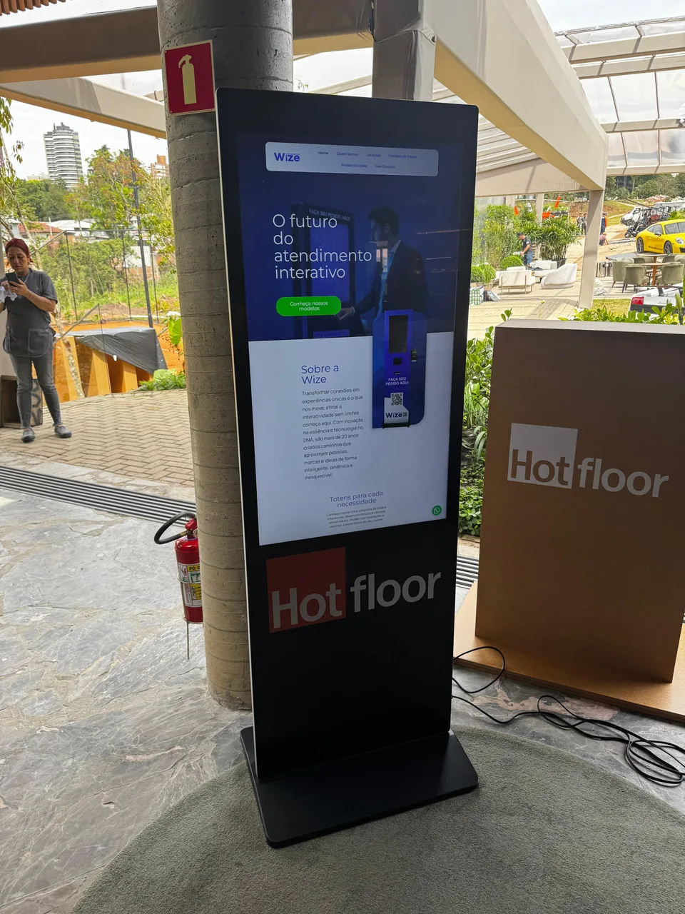 Totem interativo de 43 polegadas vertical em evento, com interface na tela e personalização da marca